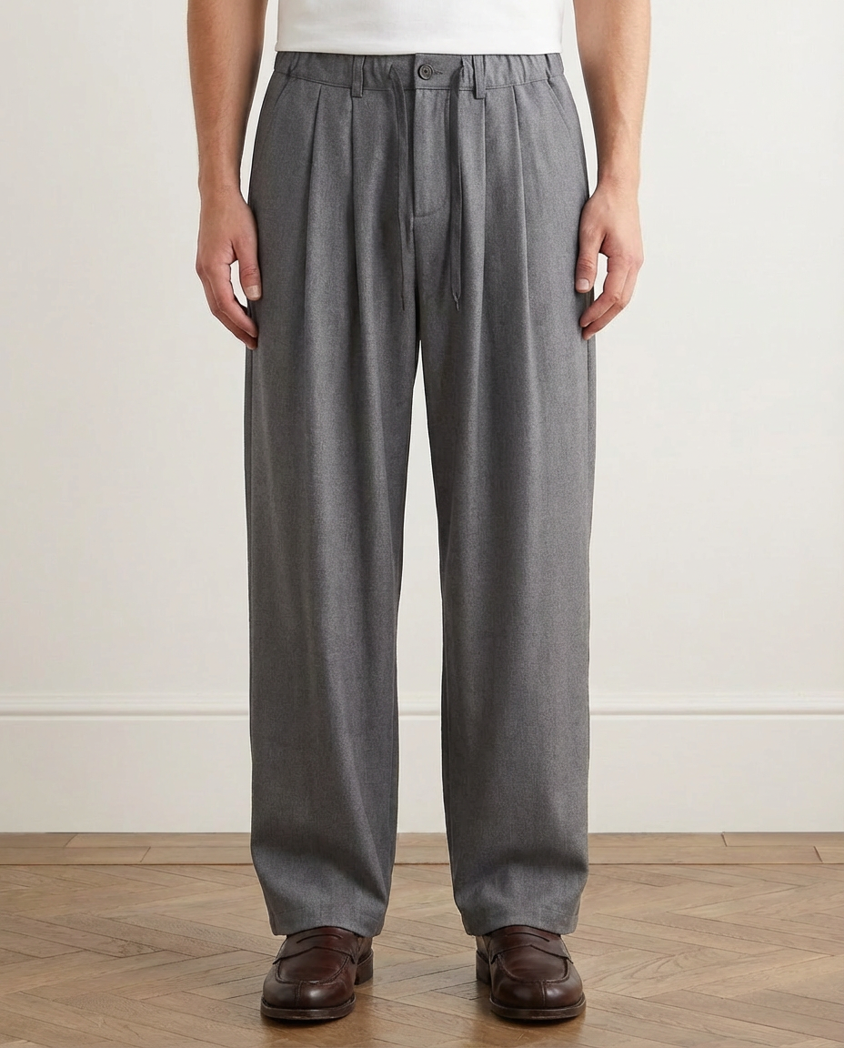 Person wearing gray pleated pants on a plain background