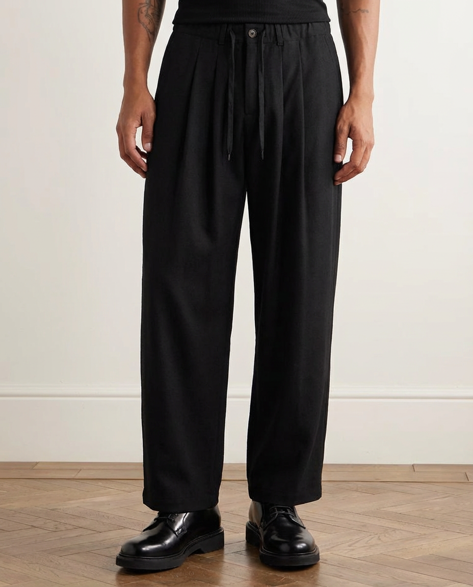 Person wearing black wide-leg pants and black shoes on a wooden floor.