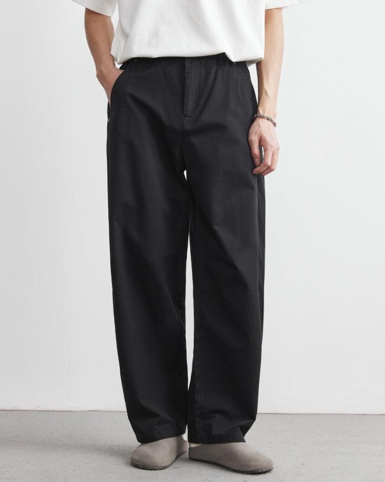 Person wearing black pants and a white shirt on a plain background