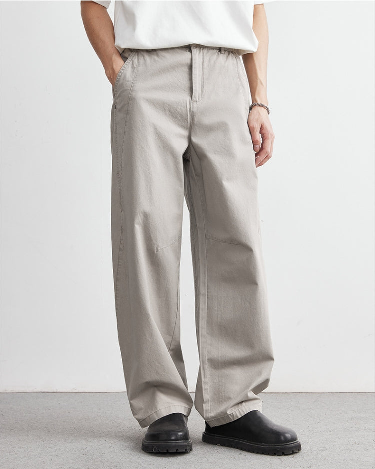Person wearing beige wide-leg pants and black shoes on a plain background