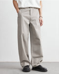 Person wearing beige wide-leg pants and black shoes on a plain background
